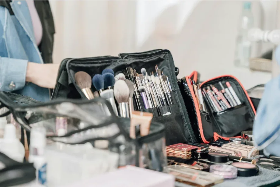 Maletín abierto con brochas, pinceles y paletas de maquillaje sobre una mesa.