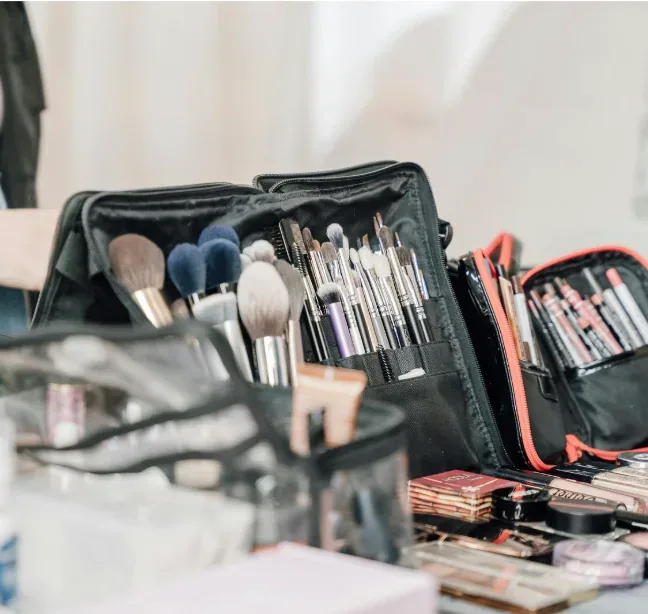 Maletín abierto con brochas, pinceles y paletas de maquillaje sobre una mesa.